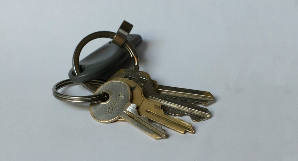 House keys with keyring and remote fob on white background